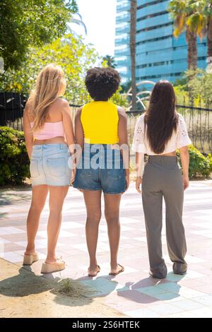 Rückansicht drei junge Frauen, die mit Einkaufstaschen im Freien in der Stadt spazieren gehen Stockfoto