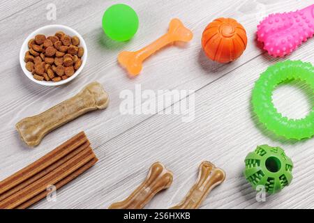 Trockenfutter für Hunde. Granuliertes Tierfutter in einer Schüssel und künstliches Hundekauen Knochenfutter mit Vitaminen. Spielerische Spielzeuge wie Kugeln, Gummiring und ch Stockfoto