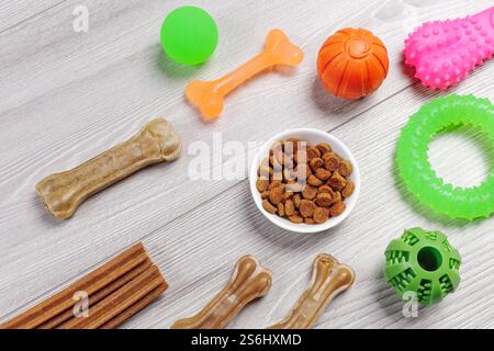 Trockenfutter für Hunde. Granuliertes Tierfutter in einer Schüssel und künstliches Hundekauen Knochenfutter mit Vitaminen. Spielerische Spielzeuge wie Kugeln, Gummiring und ch Stockfoto
