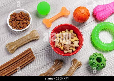 Trockenfutter und spielerisches Spielzeug für Hunde. Granuliertes Tierfutter in Schüsseln und künstliches Hundekauen mit Vitaminen. Bälle, einen Gummiring und Kauen Stockfoto
