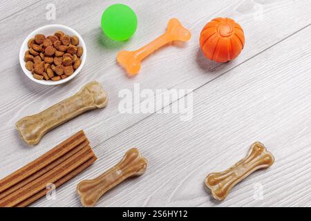 Trockenfutter und spielerisches Spielzeug für Hunde. Granuliertes Tierfutter in einer Schüssel und künstliches Hundekauen Knochenfutter mit Vitaminen. Bälle, ein Kauknochen auf dem Kaugummi Stockfoto