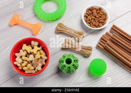 Trockenfutter und spielerisches Spielzeug für Hunde. Granuliertes Tierfutter in Schüsseln und künstliches Hundekauen mit Vitaminen. Bälle, ein Gummiring und ein Kaugummi Stockfoto