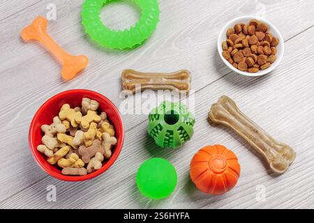 Trockenfutter und spielerisches Spielzeug für Hunde. Granuliertes Tierfutter in Schüsseln und künstliches Hundekauen mit Vitaminen. Bälle, ein Gummiring und ein Kaugummi Stockfoto