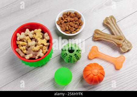 Trockenfutter und spielerisches Spielzeug für Hunde. Granuliertes Tierfutter in Schüsseln und künstliches Hundekauen mit Vitaminen. Bälle, ein Gummiring und ein Kaugummi Stockfoto