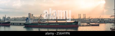Abu Dhabi, VAE - 3. Januar 2025: Panoramablick auf einen belebten Hafen mit einem Schiff der Zhejiang Shipping vor dem Hintergrund der Stadt Stockfoto