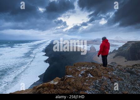 Blick auf Männer, die den Strand Solheimfjara von der Klippe Dyrhólaey bei Sonnenuntergang bewundern. Vík í Mýrdal, Südisland, Island, Nordeuropa. Stockfoto