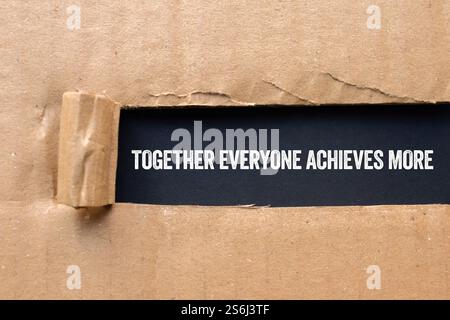 Gemeinsam erreicht jeder mehr Botschaft, die auf zerrissenem Papppapier auf schwarzem Hintergrund geschrieben wird. Konzeptionell gemeinsam erreicht jeder mehr Symbol. Stockfoto