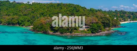 Üppige bewaldete Insel mit Sandstrand und Booten in Thailand Stockfoto