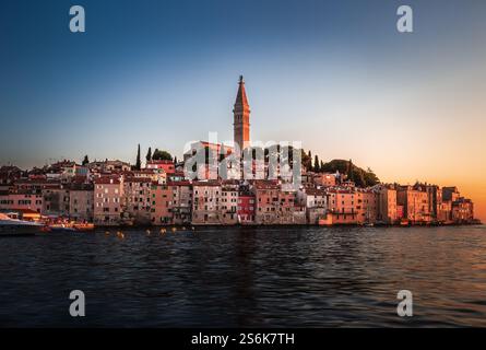Rovinj, Kroatien - Blick bei Sonnenuntergang auf die wunderschöne Altstadt von Rovinj mit dem Turm der Kirche Saint Euphemia an der Adriaküste. Klarer blauer Himmel, goldener Su Stockfoto