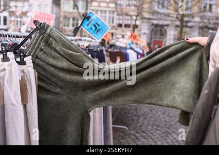 Frau, die Kleidung auf einem Flohmarkt im Freien in belgien auswählt. Belgien Tourismus Stockfoto