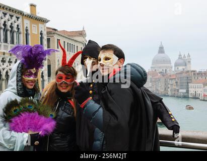 VENEDIG, ITALIEN - 14. FEBRUAR 2015: Touristen in Masken werden an der Accademia-Brücke mit Blick auf den Canal Grande fotografiert. Stockfoto
