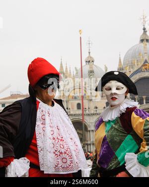 VENEDIG, ITALIEN - 14. FEBRUAR 2015: Menschen in Karnevalskostümen auf dem Markusplatz mit Markusdom im Hintergrund. Stockfoto