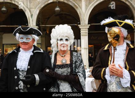 VENEDIG, ITALIEN - 14. FEBRUAR 2015: Drei Senioren in Masken am Markusplatz während des traditionellen Karnevals. Stockfoto