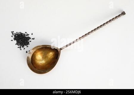 Schwarzes Sesamöl im Metalllöffel. Kopierbereich. Minimalismus. Stockfoto