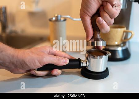 Ein Barista tönt gemahlenen Kaffee vorsichtig in einen Portafilter Stockfoto