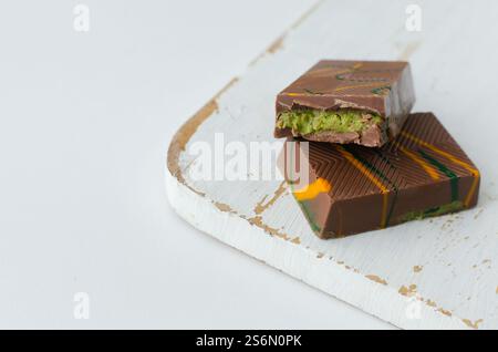 Dubai Schokolade mit Pistazienpaste und Kunefe gefüllte Milch auf dem weißen Schneidebrett auf dem Tisch. Beliebtes Essenskonzept. Horizontale Ausrichtung. Sel Stockfoto