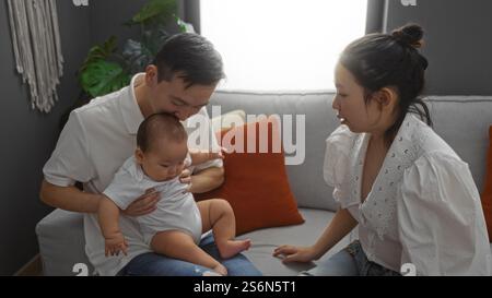 Familie verbringt Zeit zusammen in einem gemütlichen Wohnzimmer mit Mutter, Vater und Baby und genießt einen ruhigen Moment drinnen. Stockfoto