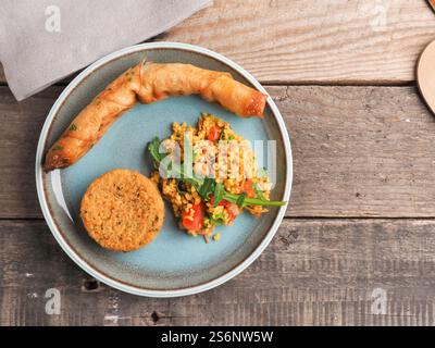 Leckere Falafel mit würzigem Bulgur und einer vegetarischen Teigrolle auf einer Keramikplatte, traditionelle hitzebehandelte Speisen, Blick von oben Stockfoto