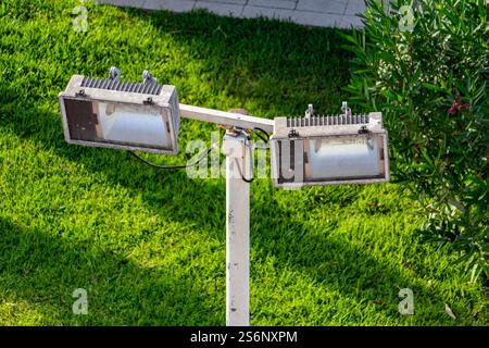 Zwei Leuchten sind auf einem Stab in einem grasbewachsenen Feld montiert. Die Leuchten sind in unterschiedlichen Höhen angeordnet, eine höher und eine tiefer, wodurch ein Gefühl von Tiefe entsteht Stockfoto