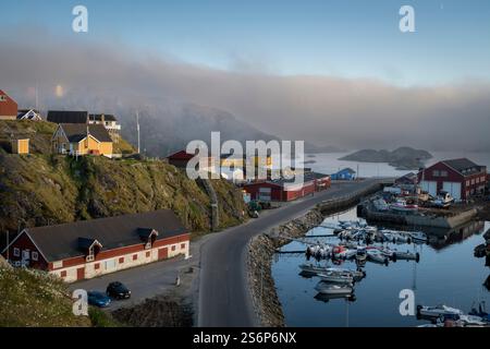 Sisimiut zeigt seinen Charme mit farbenfrohen Häusern und ruhigen Gewässern im frühen Morgenlicht und lädt zum Erkunden des malerischen Hafens ein. Stockfoto