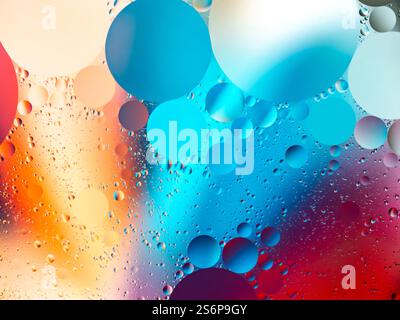 Abstraktes Bild mit kreisförmigen Formen, die durch Öl- und Wasserinteraktionen entstanden sind, mit leuchtenden, farbenfrohen Rot-, Blau- und Orangetönen für künstlerische Zwecke Stockfoto