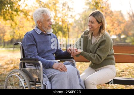 Betreuungsperson hilft Senioren im Rollstuhl im Park. Häuslicher Gesundheitsdienst Stockfoto