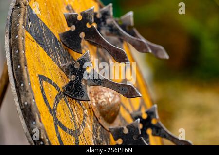 Eine Gruppe von Äxten hängt an einem Holzschild. Der Schild ist gelb und hat ein Kreuz Stockfoto