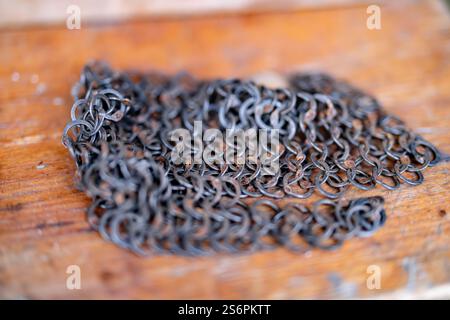 Eine Kette von Metallgliedern liegt auf einer Holzoberfläche. Die Kette ist alt und verrostet, und sie ist ein Schmuckstück. Die Szene ist etwas melancholisch Stockfoto