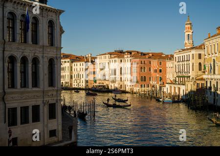 Venezianische Kanalszene: Farbenfrohe Gebäude, Gondeln und klarer Himmel. Stockfoto