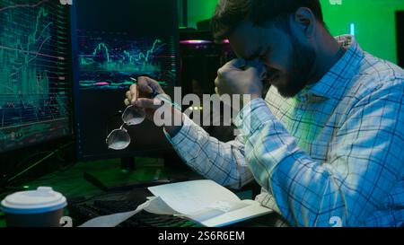 Müder arabischer indischer Mann männlicher Kerl, der Code-Monitor analysiert Computer nimmt Brillen ab, die Augen reiben Müdigkeit überarbeitete Programmiererarbeit erschöpfter Angestellter Stockfoto