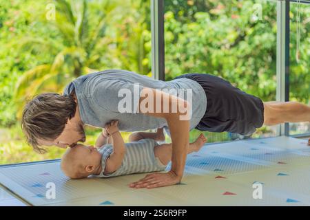 Ein Vater arbeitet mit seinem 3 Monate alten Baby, macht Liegestütze und hält inne, um sein Kind zu küssen. Ein fröhlicher und herzerwärmender Moment, der Fitness kombiniert Stockfoto