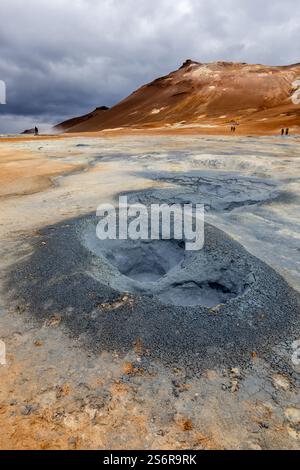 Kochender grauer Schlammtopf in Hverir, Myvatn Geothermalgebiet im Nordosten Islands, mit vulkanischer Landschaft im Hintergrund. Stockfoto