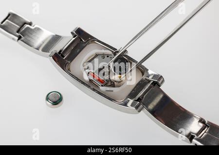 Uhrengehäuse geöffnet, Pinzette, Uhrenbatterie, Detail, weißer Hintergrund, Symbolfoto, Batteriewechsel, Uhrenreparatur, Stockfoto