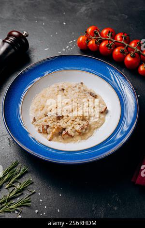 Cremiges Stachelpilz-Risotto auf blauem Teller mit Parmesan-Beilage Stockfoto