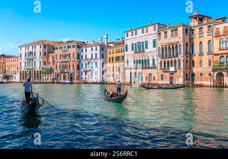 Gondeln mit Touristen auf dem Canal Grande in Venedig, Italien, mit alten traditionellen Gebäuden im Hintergrund. Stockfoto