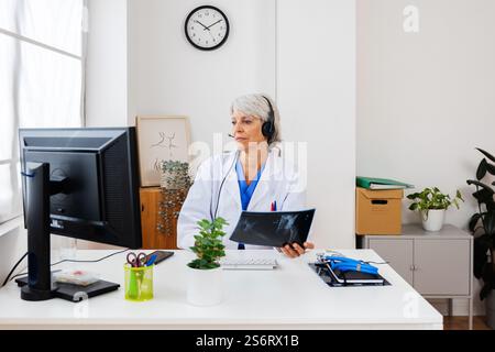 Leitende Ärztin untersucht medizinisches Röntgenbild am Schreibtisch im Krankenhaus Stockfoto