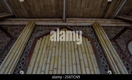 Nahaufnahme einer Bambuswand mit zylindrischen Bambusabschnitten und vertikalen Bambusstangen mit natürlichen Texturen und Mustern. Stockfoto