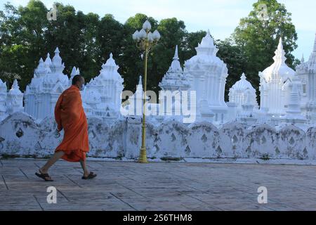 Ein Mönch, der eine Gesichtsmaske trägt, geht zum Abendgebet im Wat Suan Dok in Chiang Mai, Thailand Stockfoto