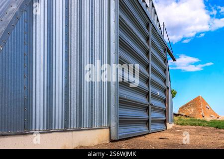 Ein großes Metallgebäude mit einer Metalltür. Die Tür ist offen und das Gebäude ist von einem grasbewachsenen Bereich umgeben Stockfoto