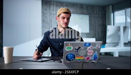 Glückliche junge männliche Designer mit Laptop im Büro Stockfoto
