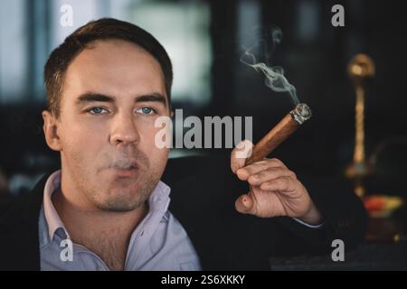 Ein Mann raucht eine Zigarre und der Rauch wird aus dem Mund freigesetzt Stockfoto