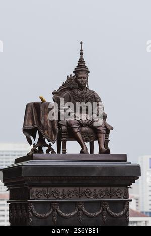 Eine detaillierte Bronzestatue eines sitzenden thailändischen Königs in traditioneller königlicher Kleidung. Stockfoto
