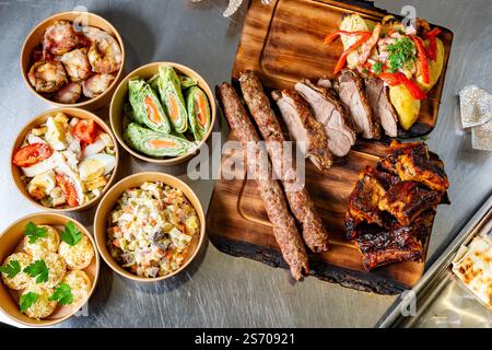 Eine lebendige Auswahl an gegrilltem Fleisch, einschließlich Rippchen und Spießen, kombiniert mit frischen Salaten und Beilagen, die ein fest perfekt für Versammlungen oder ce darstellen Stockfoto