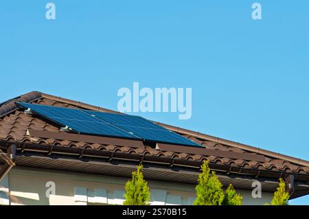 Solarpaneele, die auf einem schrägen Dach eines Wohnhauses unter klarem Himmel installiert sind. Stockfoto