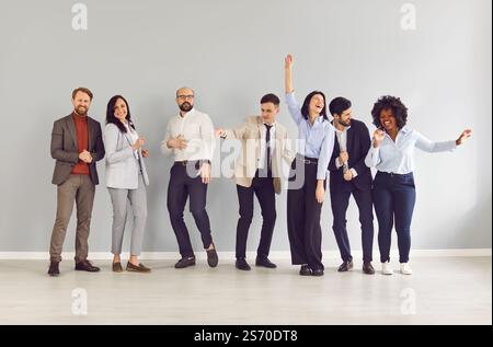 Fröhliches multirassisches Business-Team, das in Reihe steht, tanzt und Wochenende für Arbeitstag feiert. Stockfoto