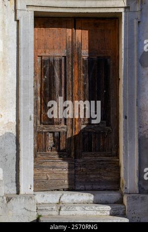 Verwitterte Holztür in einem Steingebäude mit Stufen. Alte Holz- und Steinstrukturen. Stockfoto