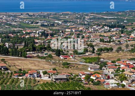 Aus der Vogelperspektive auf das antike Korinth, Griechenland, mit dem Tempel des Apollo, historischen Ruinen, traditioneller Architektur und dem malerischen Golf von Korinth. Stockfoto