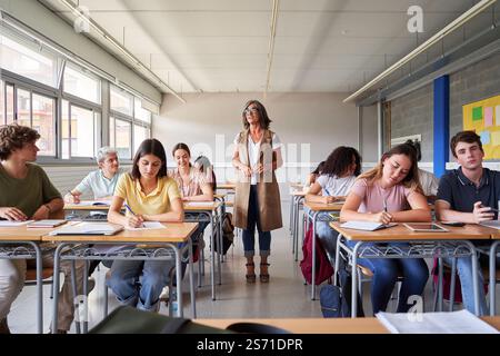 Der Lehrer beobachtet die Schüler, die im Klassenzimmer eine Prüfung ablegen. Stockfoto