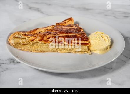 Scheibe Galette des rois (Kings Pie) mit Vanilleeis auf einem Teller. Es besteht aus Blätterteig und Mandelfrangipan und verbirgt einen Charme. Serviert am Stockfoto
