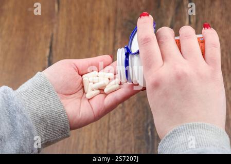 Eine junge Frau, die Pillen in ihre Handfläche gießt. Medizin und Gesundheitskonzept. Stockfoto